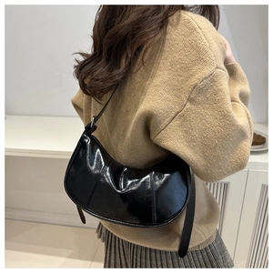 Detail of glossy black patent leather crescent shoulder bag with adjustable strap