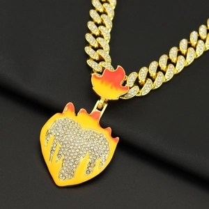 Close-up of gold Cuban chain necklace with sparkling rhinestone heart flame pendant