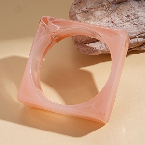 Close-up of pink marbled acrylic square bangle on natural stone background