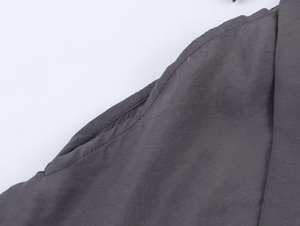 Close-up of dark grey fabric texture and high-quality stitching on shoulder bow shirt