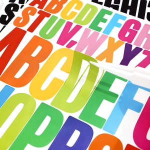 Close-up of tweezers peeling a green letter sticker from a colorful vinyl set