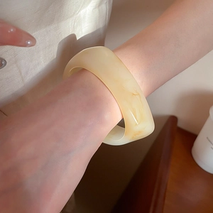 Primer plano de brazalete ancho de resina crema con textura de mármol en la muñeca