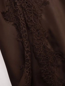 Detailed close-up of dark brown satin fabric with intricate matching lace trim