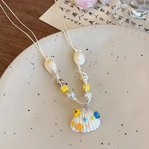 Gros plan du collier style plage avec pendentif en coquillage et perles colorées