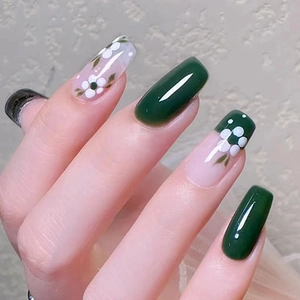 Detail of long square press-on nails with green floral and white polka dot patterns