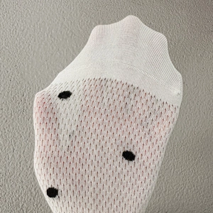 Detail showing the breathable knitted mesh fabric and polka dot pattern of white socks