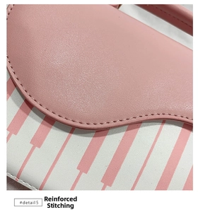 Detail shot of reinforced stitching on the pink and white striped PU leather handbag