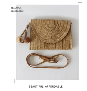 Detailed view of woven straw bag with leather strap and decorative pompom charm