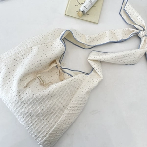 Detail of white waffle texture shoulder bag with black polka dots and blue trim