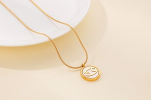 Macro detail of gold snake chain necklace featuring a Cancer zodiac shell pendant