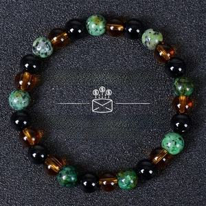 Detail of money success bracelet with tiger eye and turquoise beads on black background