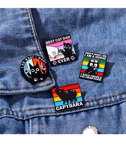 Detail of cartoon enamel pins with black cat and capybara on blue denim jacket