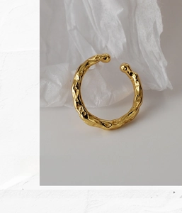 Macro detail of 18K gold textured lava finish ring on a clean minimalist background