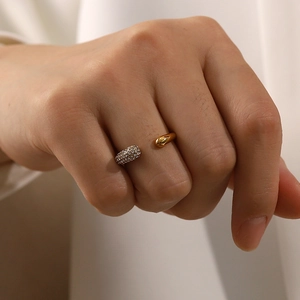 Close-up of gold open ring on finger featuring a water drop metal end and sparkling pave zircons