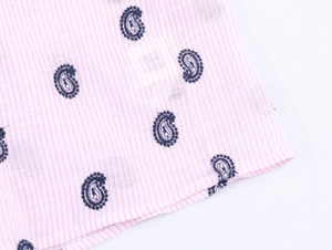 Détail du tissu à rayures roses et blanches avec broderie paisley bleue et ourlet