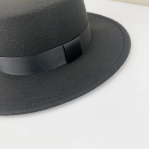 Detail of black wool felt flat brim hat showing textured ribbon band and premium finish