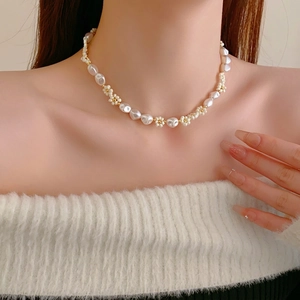 Elegant gold plated baroque pearl and flower beaded necklace worn by a female model