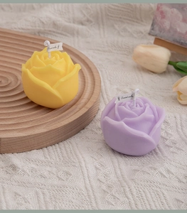 Detailed view of yellow and purple rose-shaped scented candles on a wooden tray