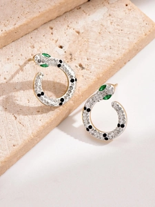 Macro shot of gold-plated snake earrings with white enamel and green zircon eyes