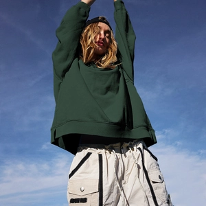 Detailed view of dark green crewneck sweatshirt and cargo pants with ribbon accents