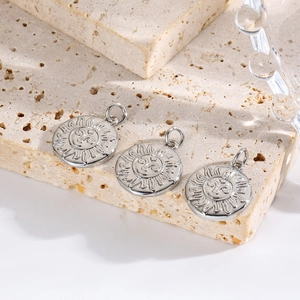 Detailed view of silver sun face relief pendants arranged on a beige travertine stone