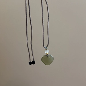 Close-up of Ruyi jade pendant with hand-woven adjustable cord and golden bead detail