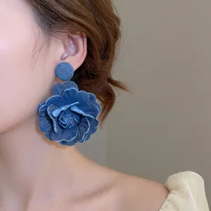 Chic 3D blue denim rose earrings with pearl accents and frayed fabric layers on model