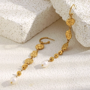 Detail of 18K gold-plated hammered metal tassel earrings with white pearls on white stone