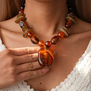 Detail view of large amber resin oval pendant on a retro geometric beaded necklace