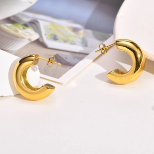 Macro detail of gold C-shaped chunky earrings with polished mirror finish and stud backing