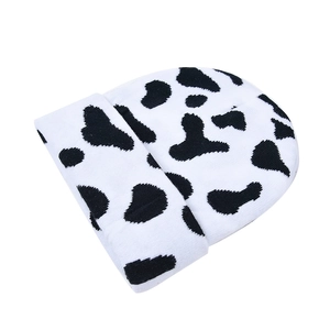 Gros plan sur la texture en maille imprimé vache noir et blanc et l'ourlet du bonnet