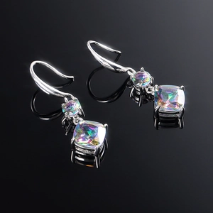 Macro detail of silver drop earrings with iridescent square zircons on black background