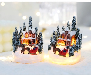 Macro shot of glowing miniature resin house with snowy trees for Christmas decor