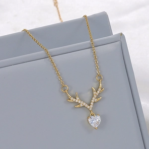 Detailed close-up of a gold reindeer antler necklace with a heart-shaped pearl pendant