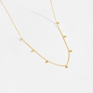 Detail of a minimalist gold S925 silver necklace with sparkling round zircon pendants
