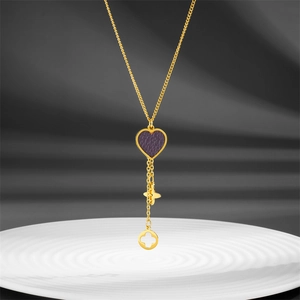 Minimalist gold titanium necklace with blue heart pendant and clover charms on white plate