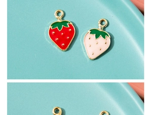 Macro shot of red and pink strawberry alloy charms with green leaves on blue background