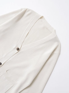 Detail of cream V-neck knit cardigan showing tortoiseshell buttons and soft texture