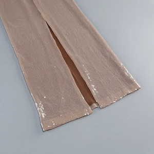 Détail d'une robe de soirée à paillettes bronze avec fente haute et texture scintillante