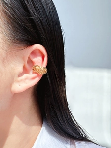 Close-up of a gold hollow chain ear cuff worn by a model to show texture and fit
