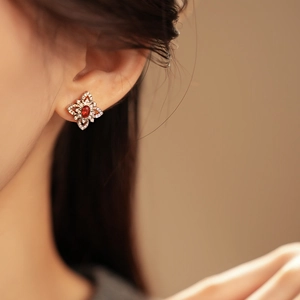 Close-up of diamond rhombus stud earring featuring a vibrant red ruby on model