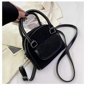 Detail of black faux suede handbag with soft white shearling front pocket and PU leather handle