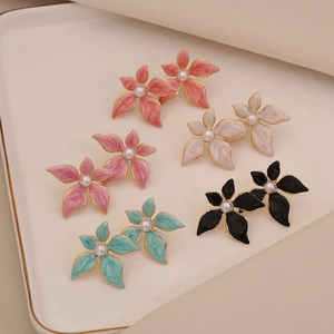 Detailed close-up of five pairs of enamel flower stud earrings with pearls on a tray