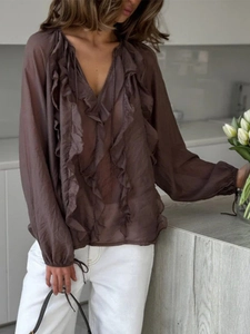 Detail of brown sheer v-neck blouse with ruffled layers and lantern sleeve design