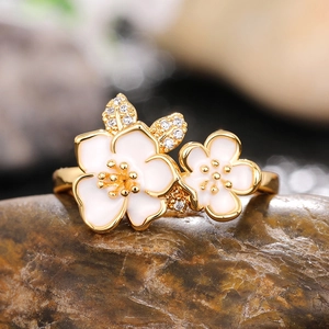 Detailed macro view of gold camellia flower ring with white enamel and sparkling crystals