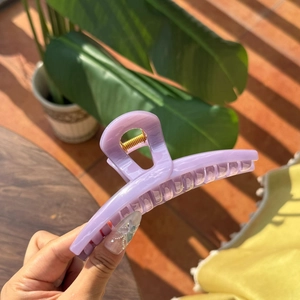 Close-up of translucent lavender butterfly hair claw clip with golden metal spring detail