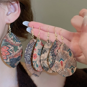 Detail of bohemian teardrop earrings with ethnic leaf patterns and faux leather texture