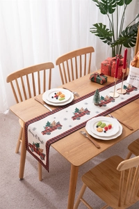 Detail view of a Christmas table runner with a red vintage truck and festive ornaments