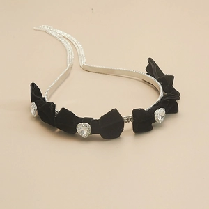 Macro detail of black velvet headband with sparkling diamond bows and heart crystals
