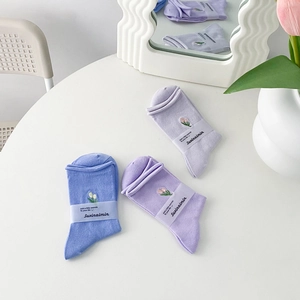 Pastel cotton crew socks with floral embroidery in purple and blue shades on white table